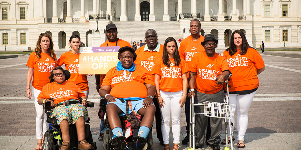Group of people in front of the U.S. Capitol wearing orange "disability rights are human rights" t-shirts